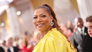 Queen Latifah, wearing a bright yellow outfit, smiles for the cameras before hosting the 2024 NCAAP Image Awards 