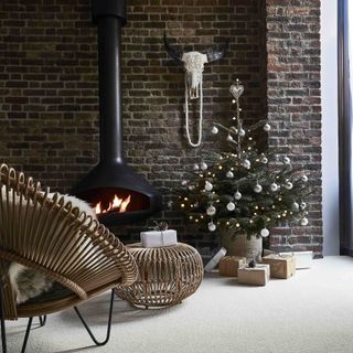 A living room with a decorated Christmas tree and a burning fireplace