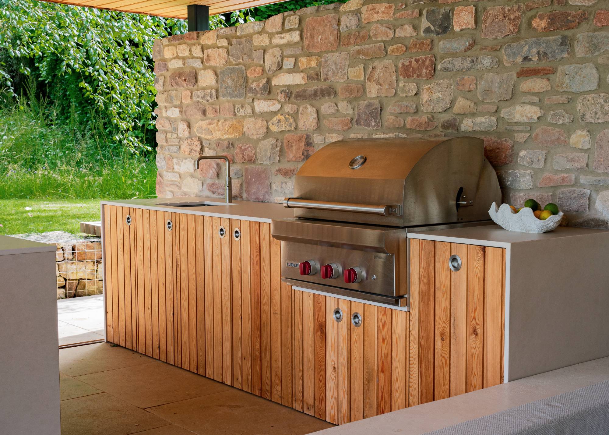 wood and stone outdoor kitchen with gas burner and steel sink