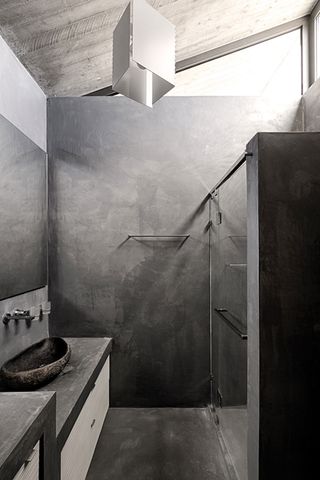 The gray concrete-looking bathroom includes the sink area to the left and a shower to the right.