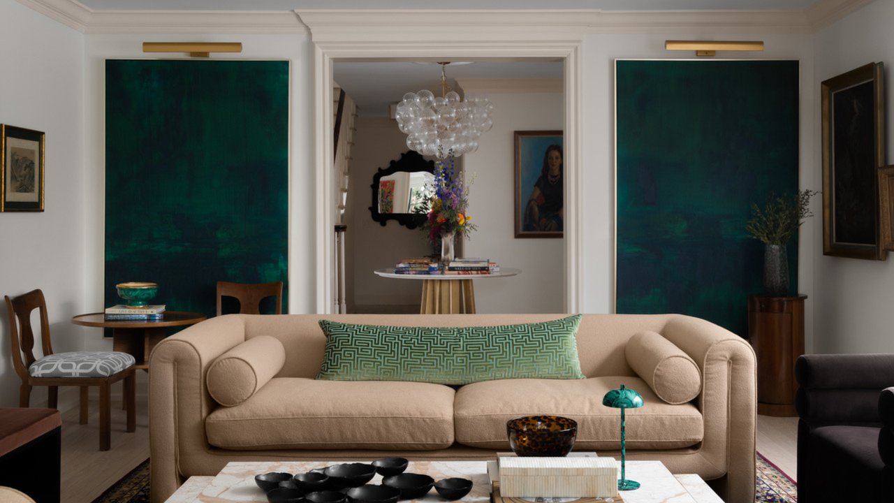 a symmetrical room with a large tan couch, matching artwork on either side of the back wall, and a doorway that leads into the next room