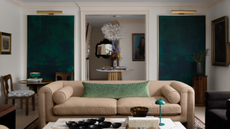 a symmetrical room with a large tan couch, matching artwork on either side of the back wall, and a doorway that leads into the next room