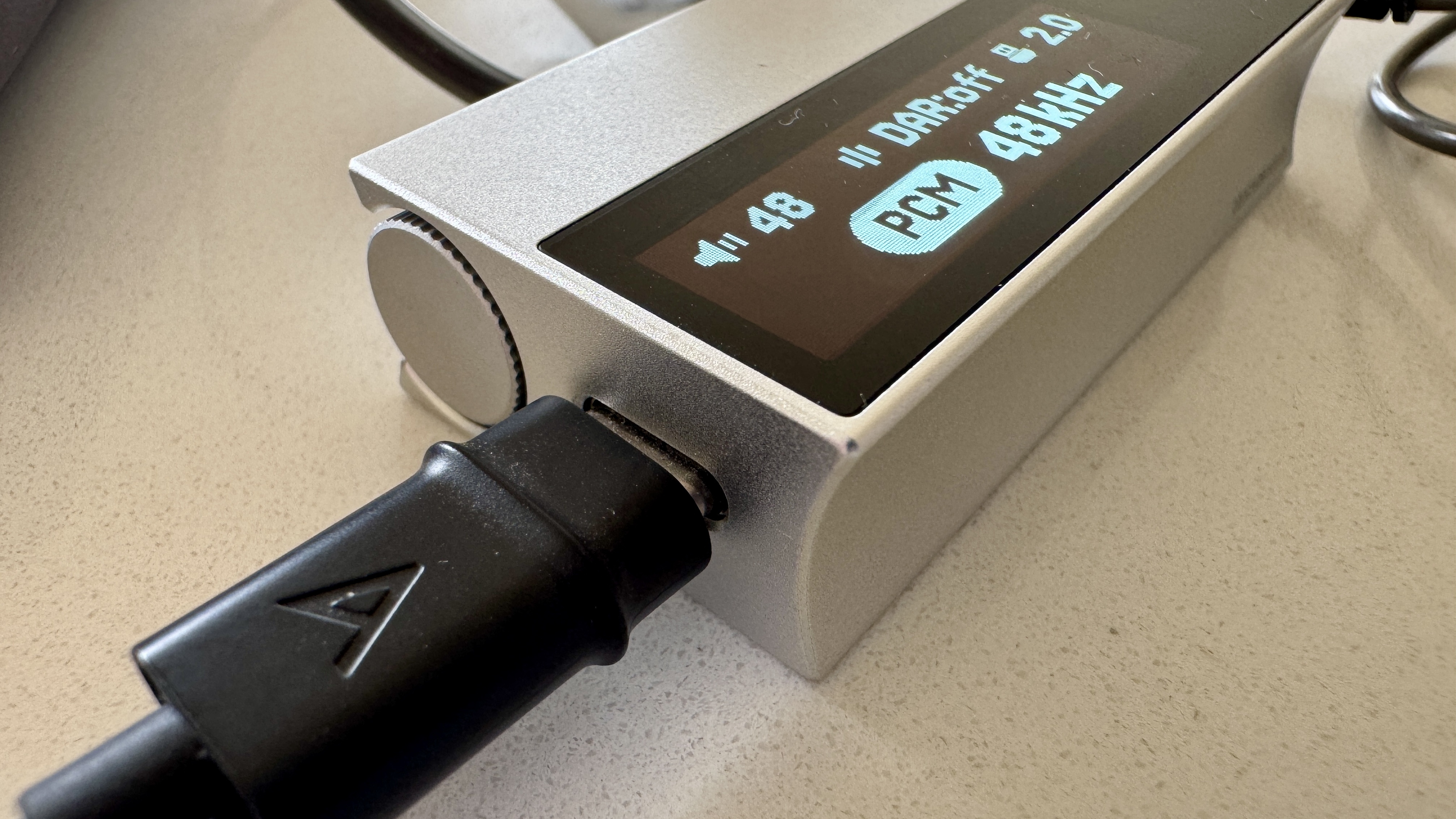 The Astell & Kern AK HC5 on a grey table, with the top plate illuminated and hooked up to Sennheiser IEMs and a FiiO digital audio player