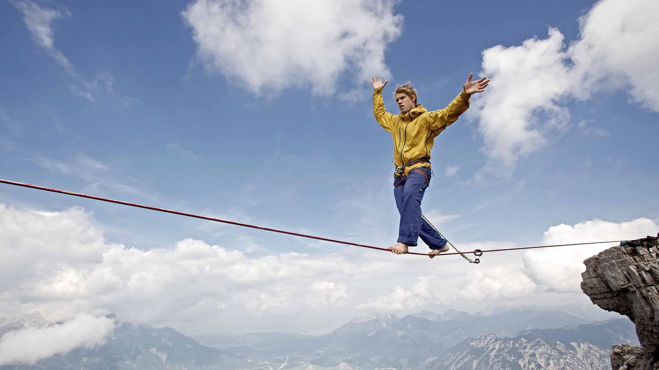 A man walks a tightrope in the mountains