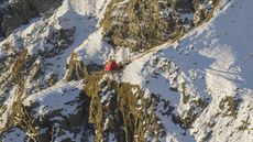 Frattini Bivouac mountain shelter, a small red structure seen among rock snowy mountains