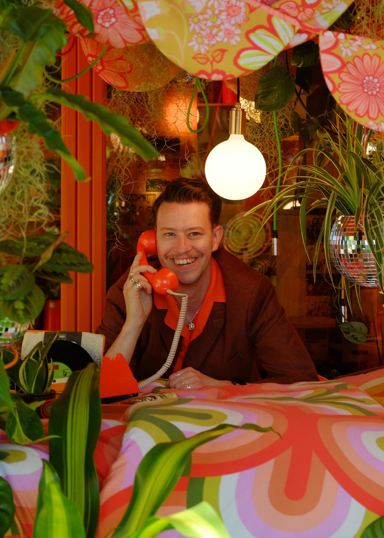 A headshot of James Whiting in a retro-style houseplant nook