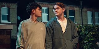 Joe Locke as Charlie and Kit Connor as Nick, standing outside some houses at night, in 'Heartstopper' season 3.