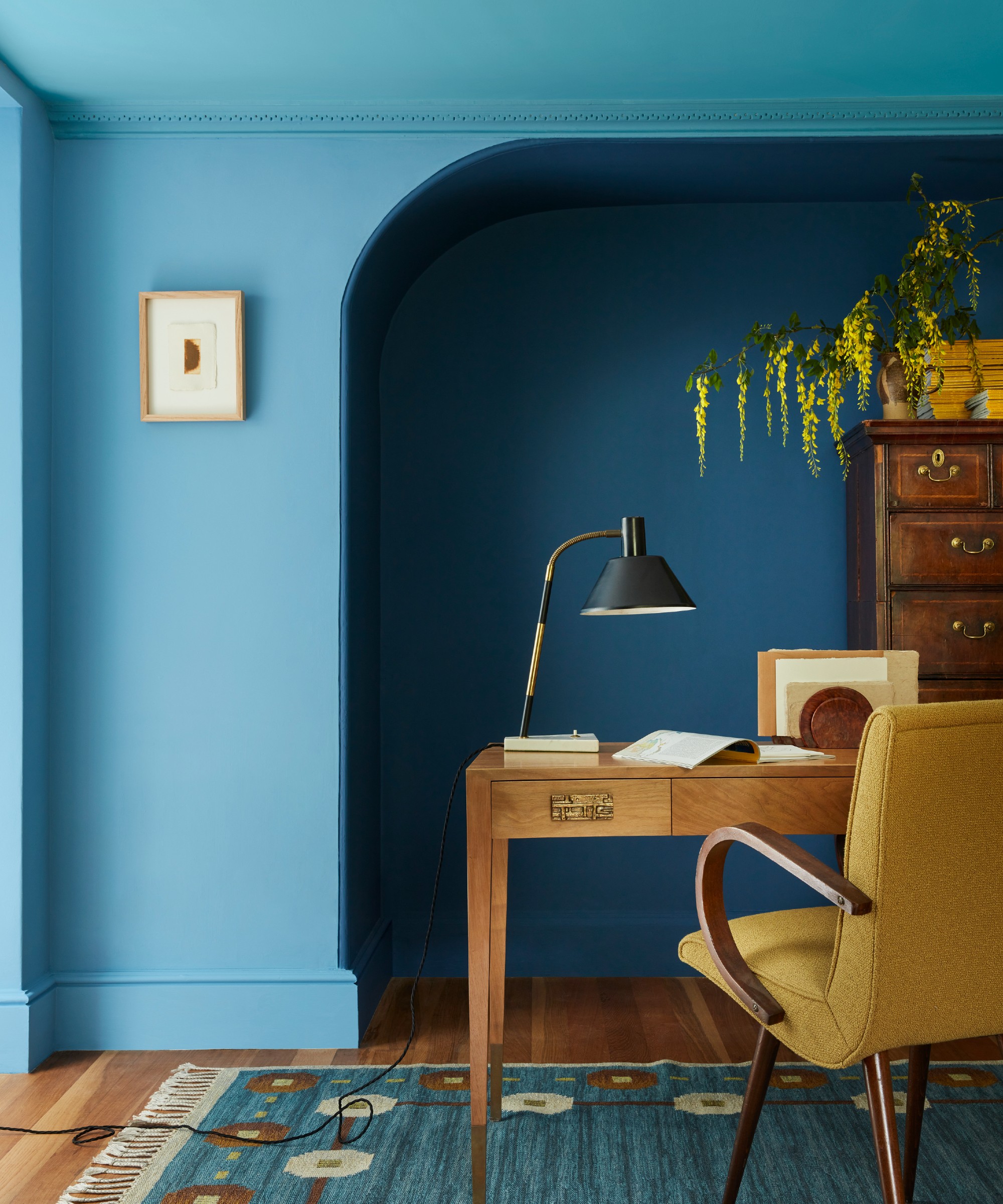 Double-drenched home office with blue walls and a ceiling painted in a different tone of blue and a mustard yellow desk chair