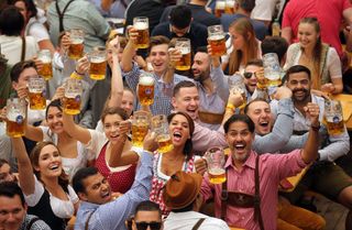 Men and women hold up beer steins at Oktoberfest