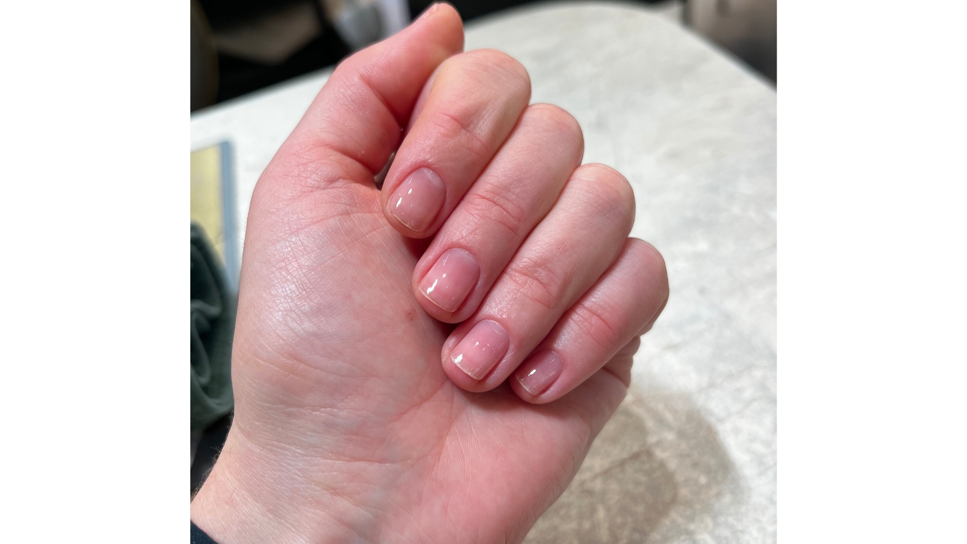 A close-up of Digital Beauty Editor, Fiona McKim's hand with short and glossy sheer nails