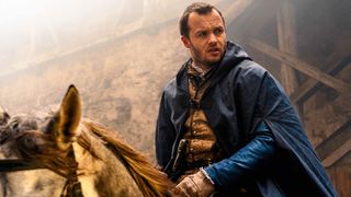 A man sits on top of a horse wearing a blue cape