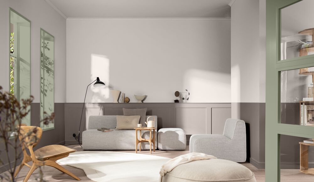 A sitting area with low, modular seating. The back wall is a white and light gray color block with sage green accents around the room.