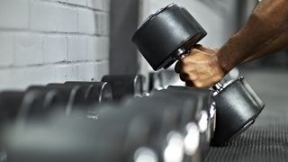 Man picking up a set of dumbbells from a rack