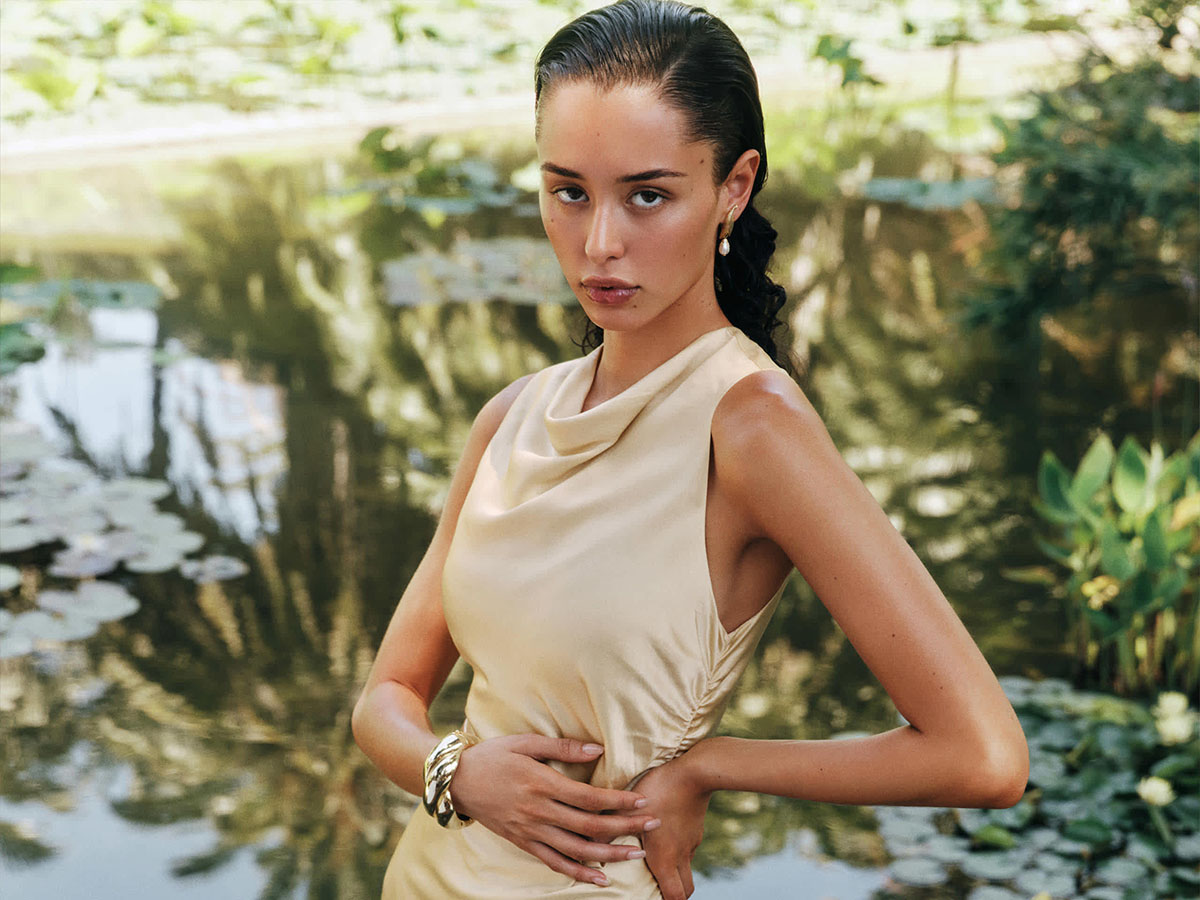 A woman wearing a silk butter yellow dress in a natural setting