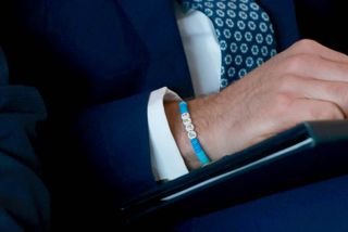 A close-up of Prince William's arm showing off a beaded blue and green bracelet that reads Papa