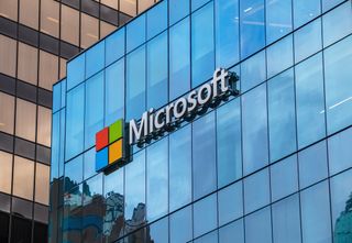 The Microsoft logo as seen in large print fixed onto a glass building