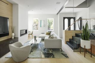 White living space with white couches, a grey rug and TV mounted to the wall at the OverUnder House in Boston
