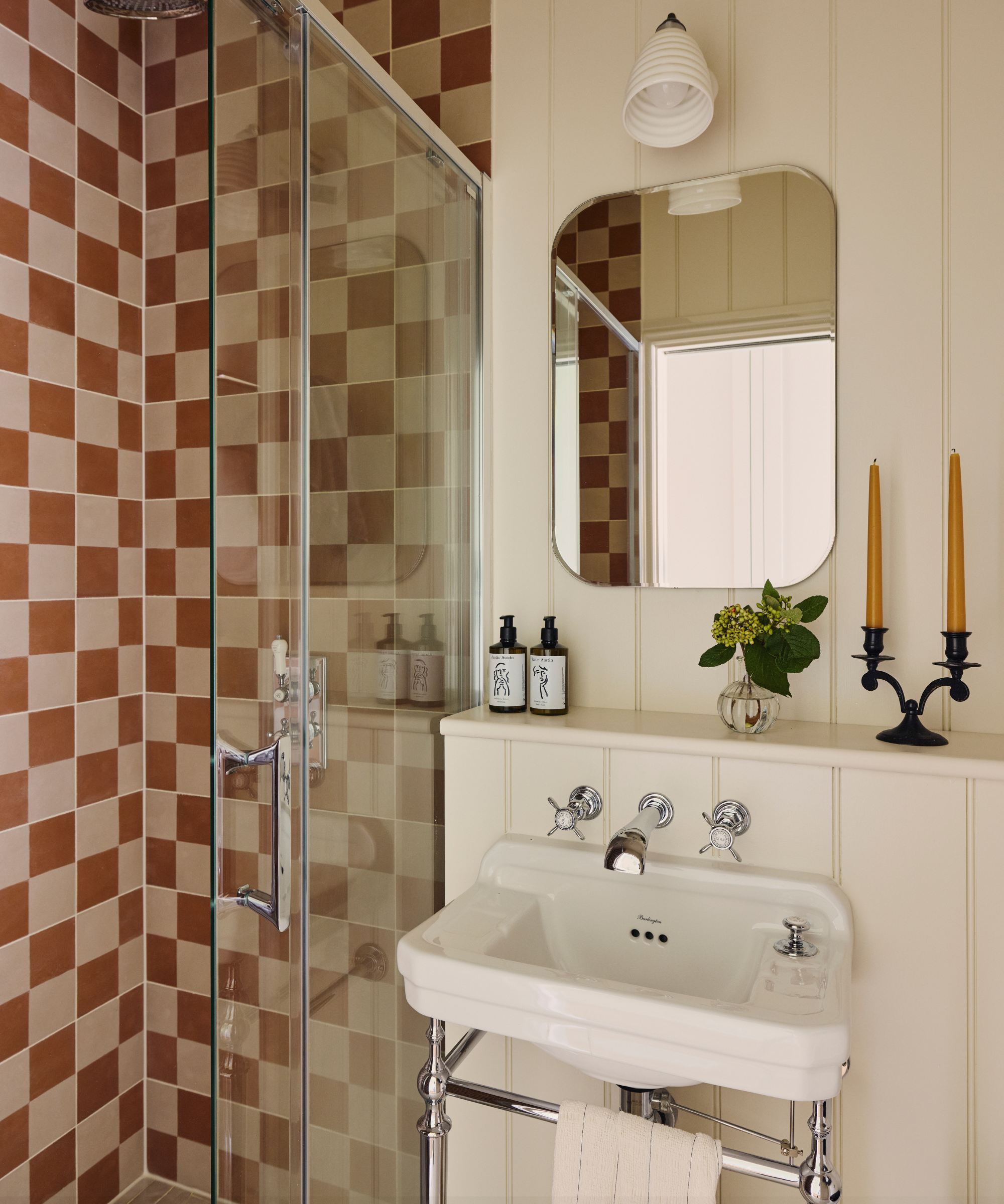 a bathroom with a checker printed wall, a small sink with silver hardware, and a mirror hanging on the wall
