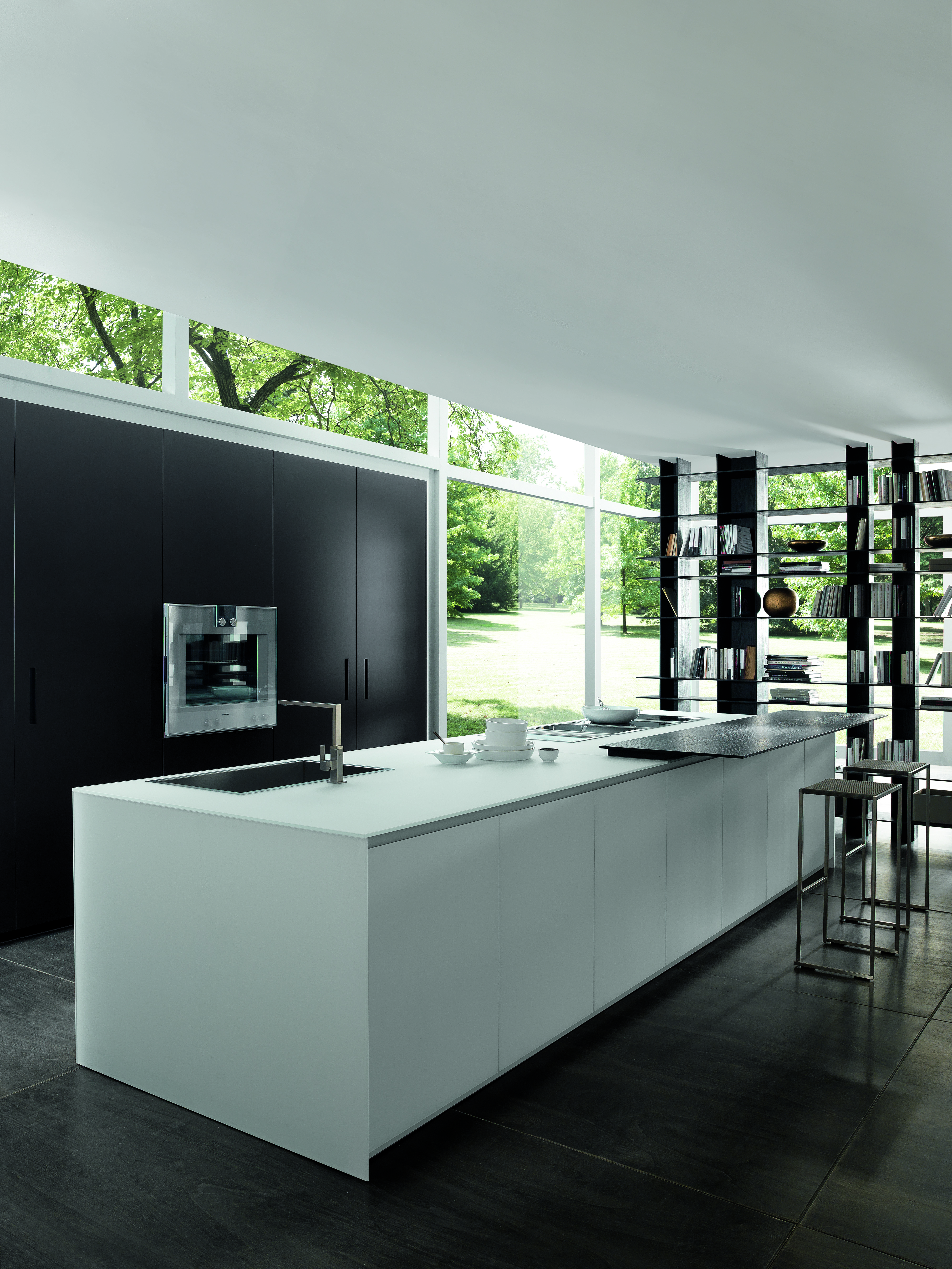 Sleeky, modern kitchen with a white kitchen island and dark wooden floors and cabinets which are one with the wall.