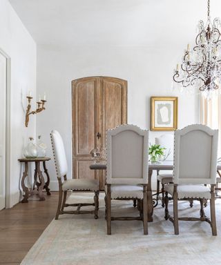 rustic dining room with vintage doors and linen chairs and a dramatic overhead chandelier