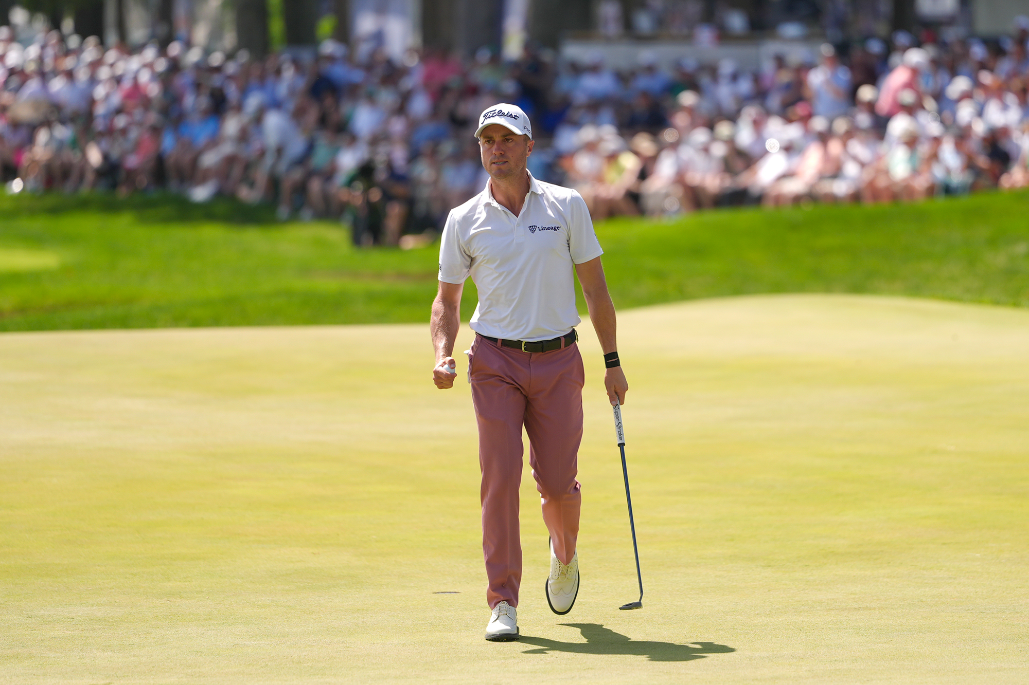 Justin Thomas celebrating a putt with a fist pump towards the crowd
