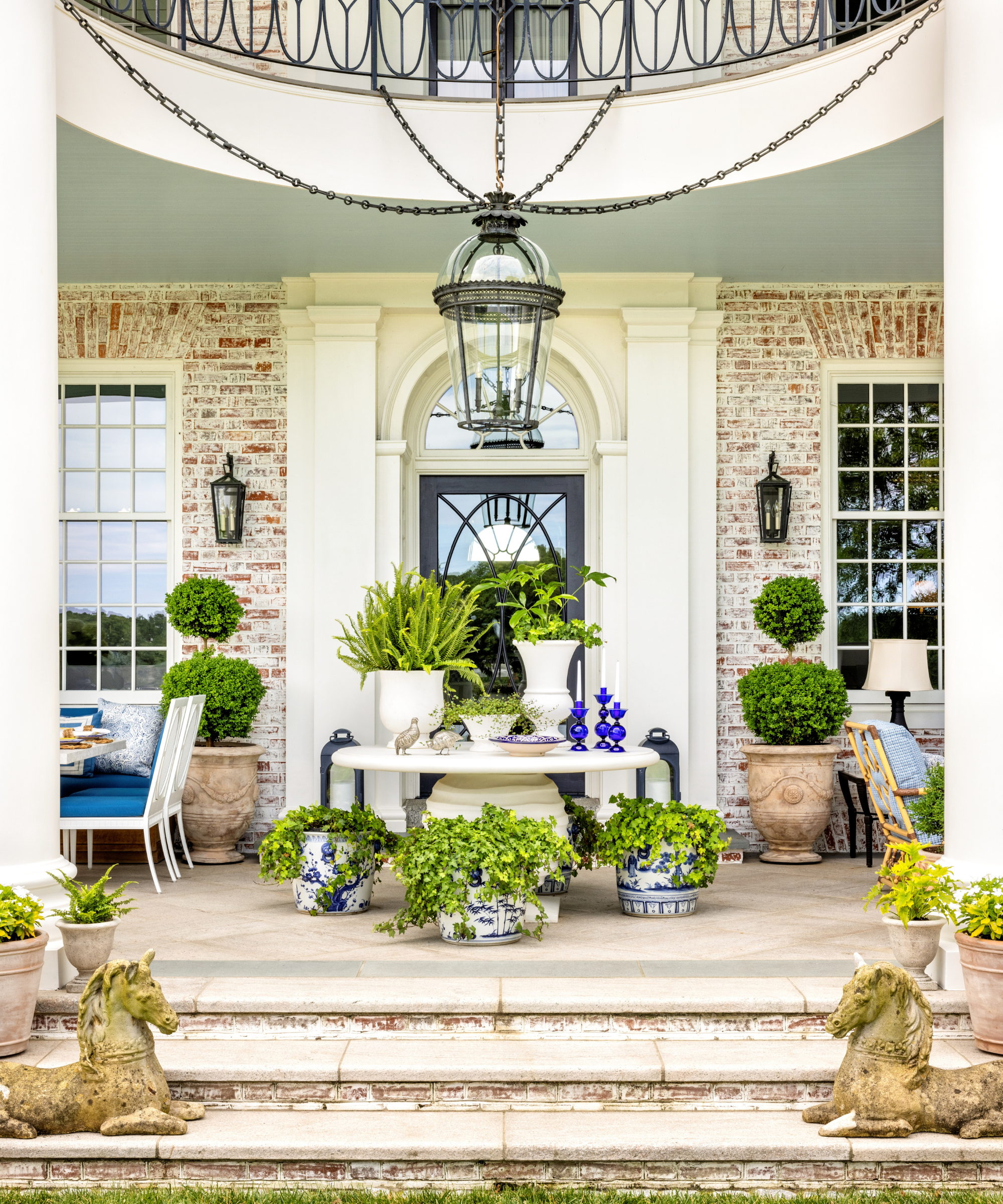 Colonial Revival back patio styled by Corey Damen Jenkins, featuring light blue and white patio furniture, lighting, and textiles.