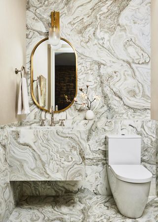 marble bathroom with gold mirror in Manhattan apartment designed by Kelly Behun