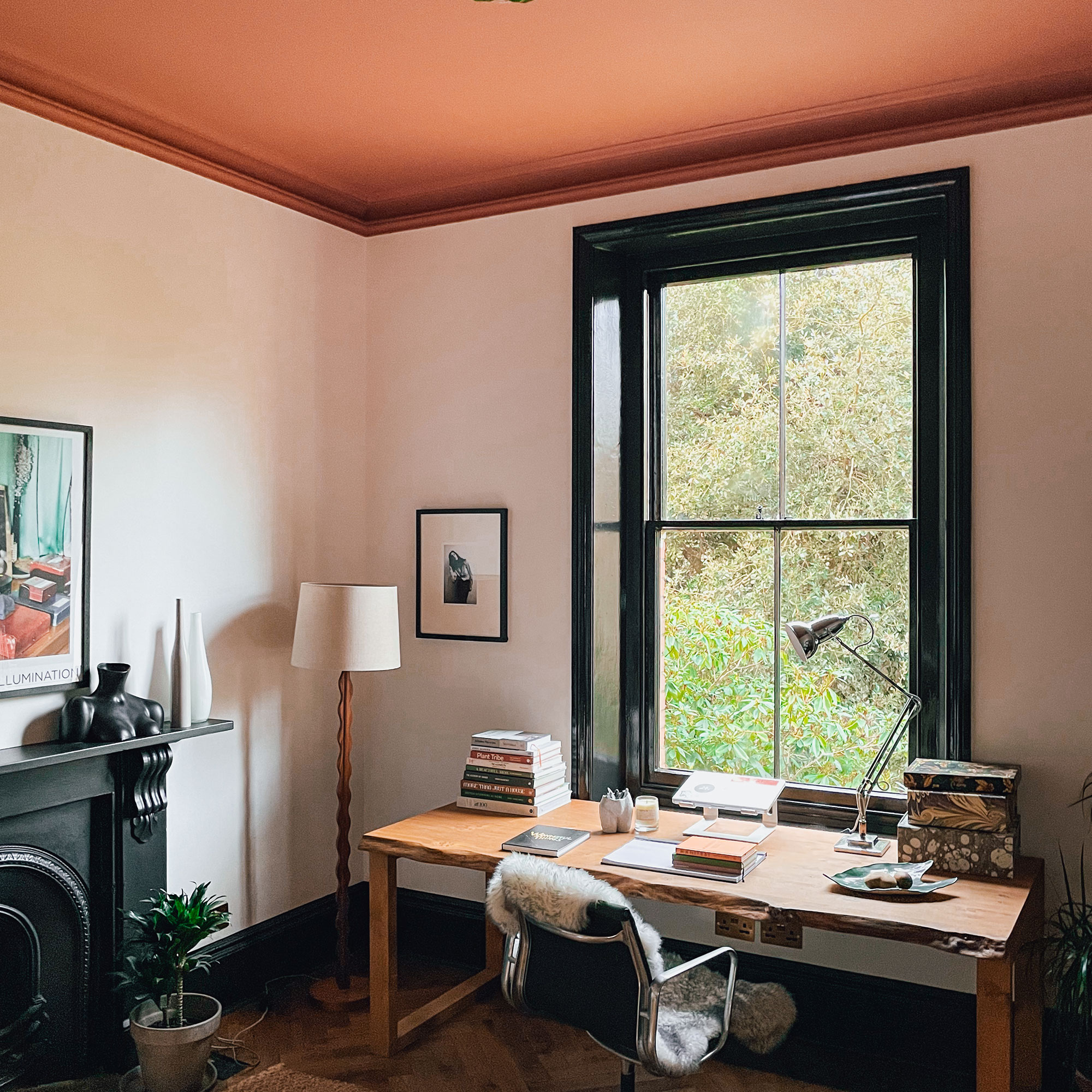 Home office with cream walls and red ceiling, large window, trimmed with black in front of wooden desk