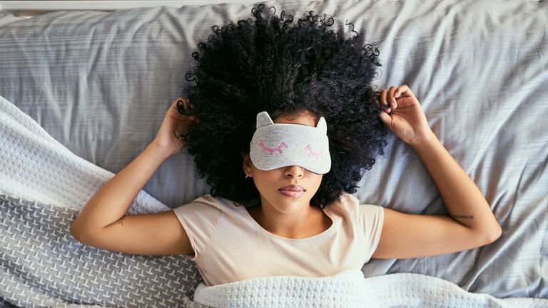 woman sleeping on her back wearing eye mask 