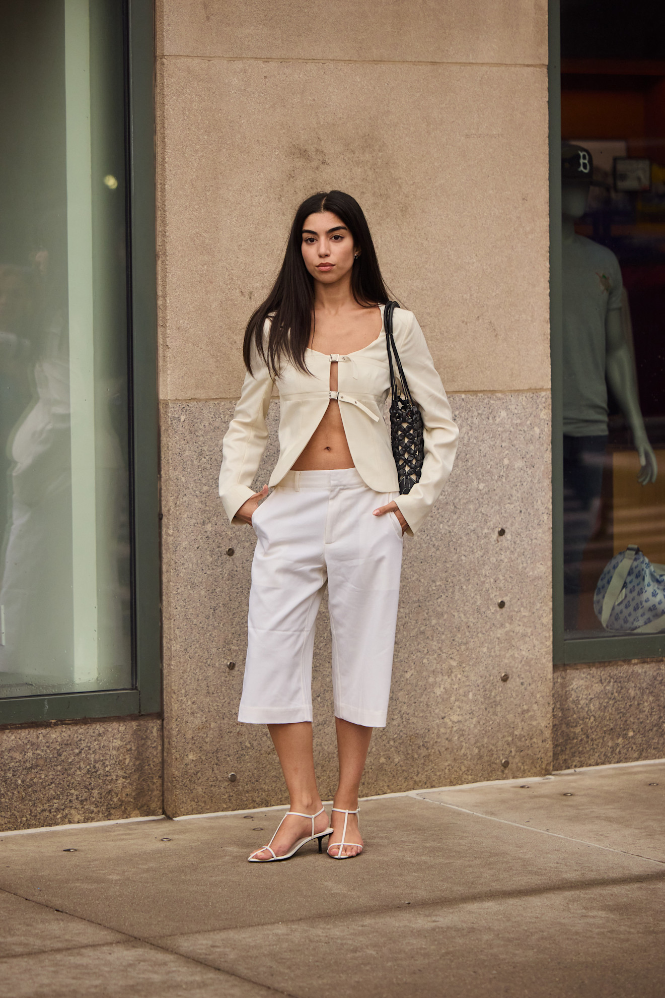 woman wearing a white blazer and burmuda shorts and white sandal heels.