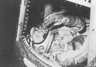Rehearsing for his historic flight on February 20, 1962, Mercury program astronaut John H. Glenn, Jr. works in a cramped training capsule preparing for a few hours' voyage through space.