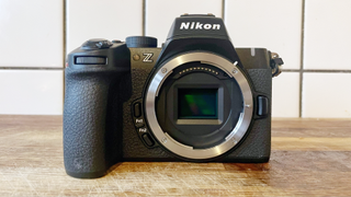 Nikon Z50 II camera on a wooden surface in front of white tiled wall