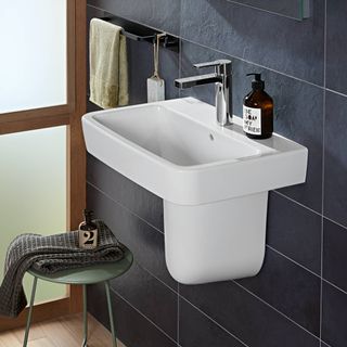 white semi pedestal sink on grey tiles in bathroom