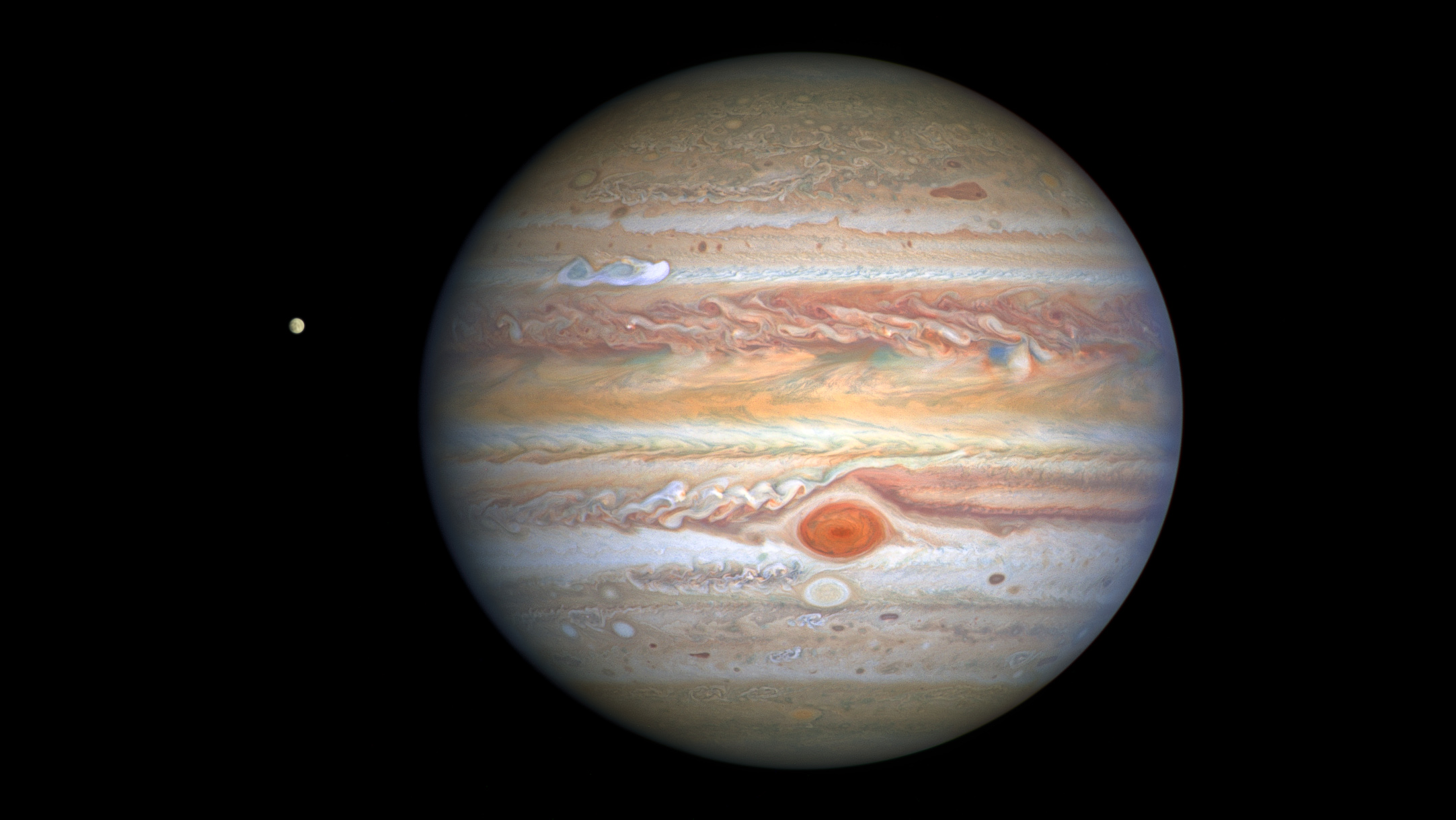 This latest image of Jupiter, taken by NASA&amp;rsquo;s Hubble Space Telescope on August 25, 2020, was captured when the planet was 406 million miles from Earth. Hubble&amp;rsquo;s sharp view is giving researchers an updated weather report on the monster planet&amp;rsquo;s turbulent atmosphere, including a remarkable new storm brewing, and a cousin of the Great Red Spot changing color &amp;ndash; again.A unique and exciting detail of Hubble&amp;rsquo;s snapshot appears at mid-northern latitudes as a bright white stretched-out storm moving at 350 miles per hour (563 kilometers per hour). This single plume erupted on August 18, 2020 and another has since appeared.While it&amp;rsquo;s common for storms to pop up in this region, oftentimes multiple at once, this particular disturbance appears to have more structure behind it than observed in storms of the past. Trailing behind the plume are small, counterclockwise-like dark clumps also not witnessed in the past. Researchers speculate this may be the beginning of a longer-lasting Northern Hemisphere spot, as perhaps a rival to the legendary Great Red Spot that dominates the southern hemisphere.Hubble shows that the Great Red Spot, rolling counterclockwise in the planet&amp;rsquo;s southern hemisphere, is plowing into the clouds ahead of it, forming a cascade of white and beige ribbons. The Great Red Spot is currently an exceptionally rich red color, with its core and outermost band appearing deeper red.Researchers say the Great Red Spot now measures about 9,800 miles across, big enough to swallow Earth. The super-storm is still shrinking as noted in telescopic observations dating back to 1930, but its rate of downsizing appears to have slowed. The reason for its dwindling size is a complete mystery.Another feature researchers are noticing has changed is Oval BA, nicknamed by astronomers as Red Spot, Jr., which appears just below the Great Red Spot in this image. For the past few years, Red Spot, Jr. has been fading in color to its original shade of white after appearing red in 2006. However, now, the core of this storm appears to be darkening to a reddish hue. This could hint that Red Spot, Jr. is on its way to turning to a color more similar to its cousin once again.Hubble&amp;rsquo;s image shows that Jupiter is clearing out its higher altitude white clouds, especially along the planet&amp;rsquo;s equator, where an orangish hydrocarbon smog wraps around Jupiter.The icy moon Europa, potential home for life, is visible to the left of the gas giant.This Hubble image is part of yearly maps of the entire planet taken as part of the Outer Planets Atmospheres Legacy program, or OPAL. The program provides yearly Hubble global views of the outer planets to look for changes in their storms, winds, and clouds.