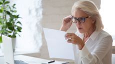 Older woman looking surprised looking at paperwork