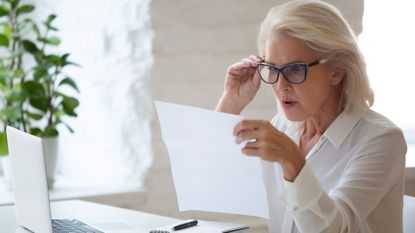 Older woman looking surprised looking at paperwork