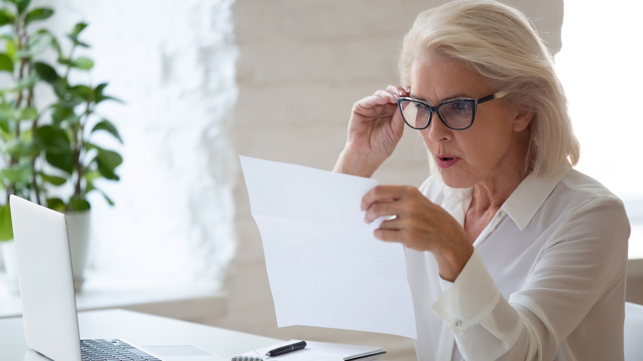 Older woman looking surprised looking at paperwork