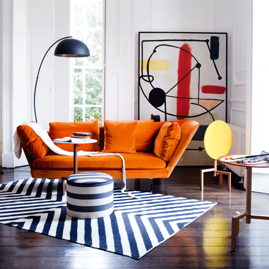 living room with white wall orange sofa and wooden flooring