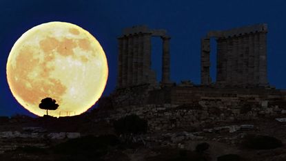 A supermoon rises behind a Greek temple