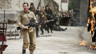 Paddy Mayne (Jack O'Connell) wielding a machine gun and shouting next to a burning vehicle in SAS Rogue Heroes season 2