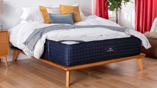 DreamCloud Luxury Hybrid mattress in a light bedroom, with colorful bedding