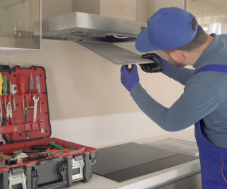 A person installing a grease filter on a cooker hood