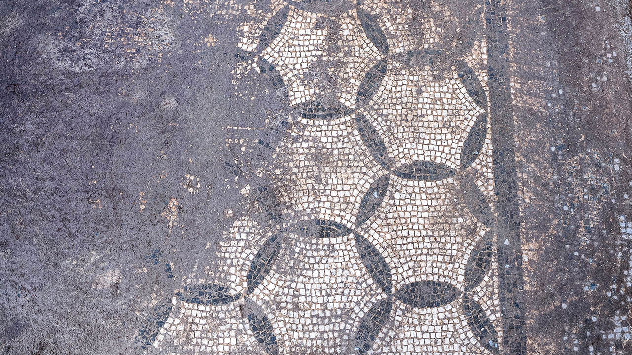 archaeologists work at an ancient Roman site revealing mosaic floors and frescoed walls of a villa