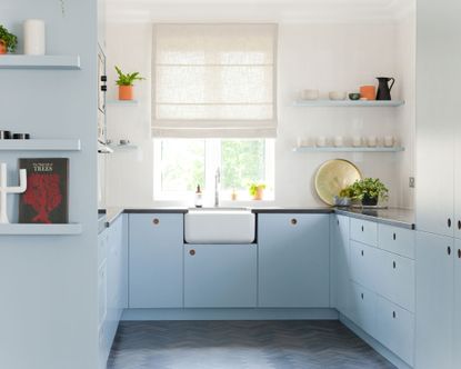  u-shaped kitchen with light blue cabinets and a white Belfast sink in front of a window