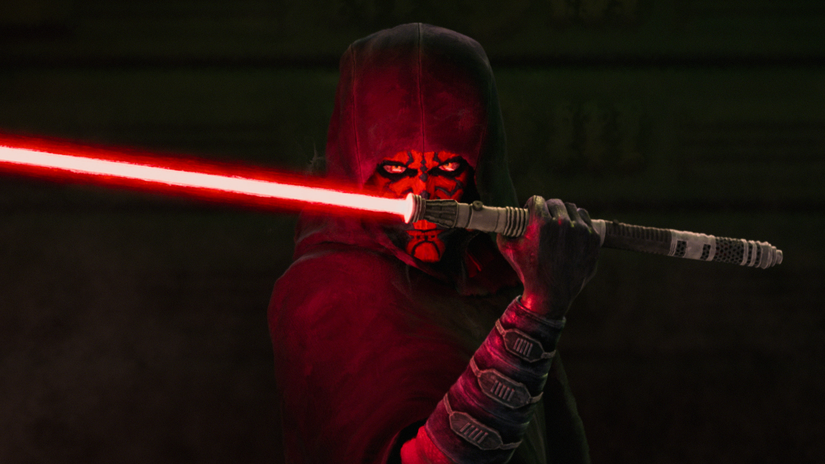 A hooded Maul (voiced by Sam Witwer) wielding his red lightsaber in a scene from "Star Wars: Maul - Shadow Lord" on Disney+.
