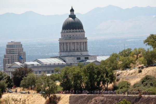 The peloton passes be the shadow of the state capitol building.