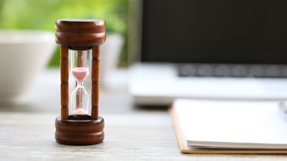 Picture of hourglass running out with computer in background