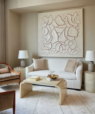 neutral living room with cream carpet neutral walls with cream artwork, cream sofa and coffee table