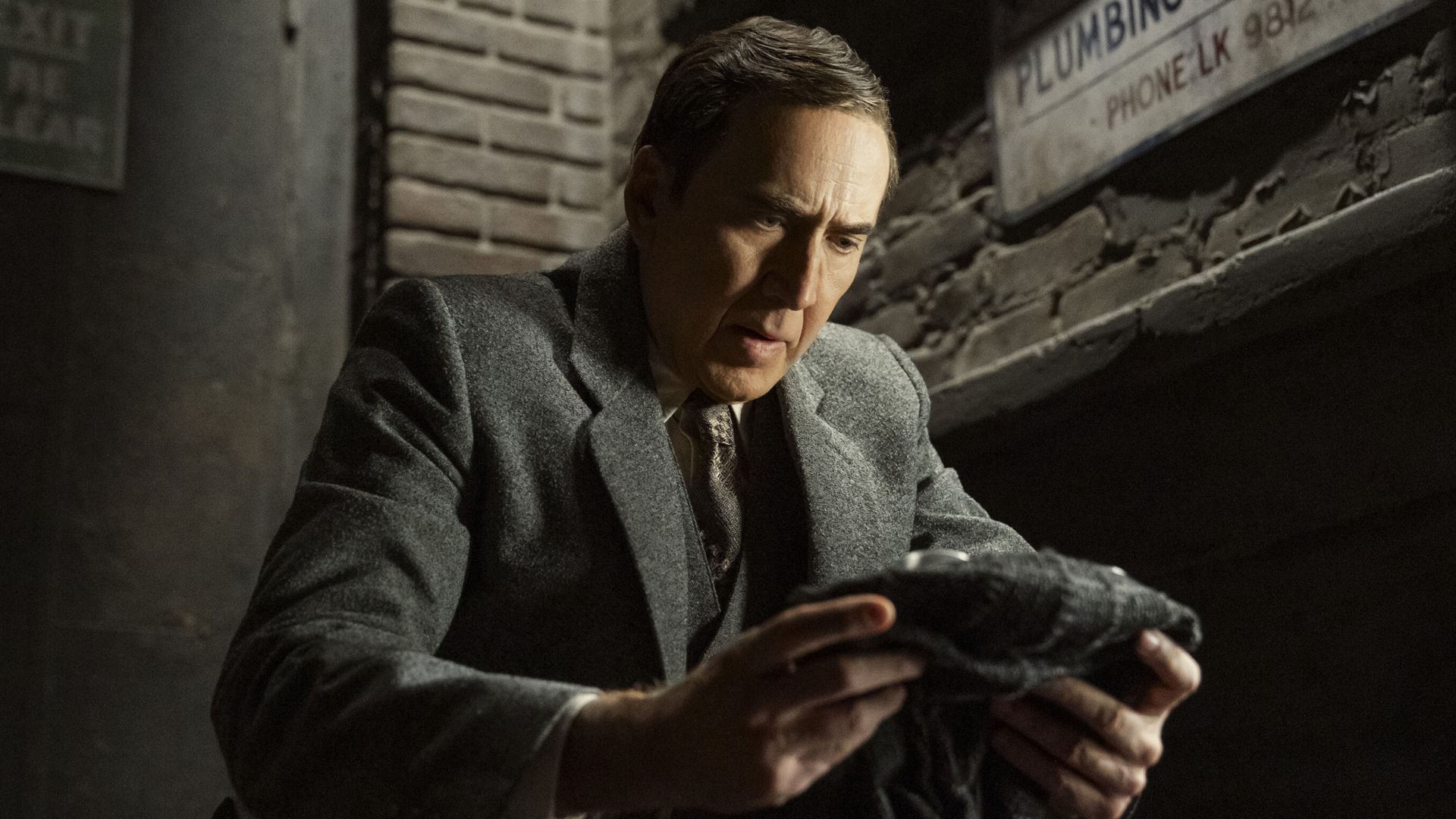 Ben Reilley (Nicolas Cage) looks at his mask on Spider-Noir.