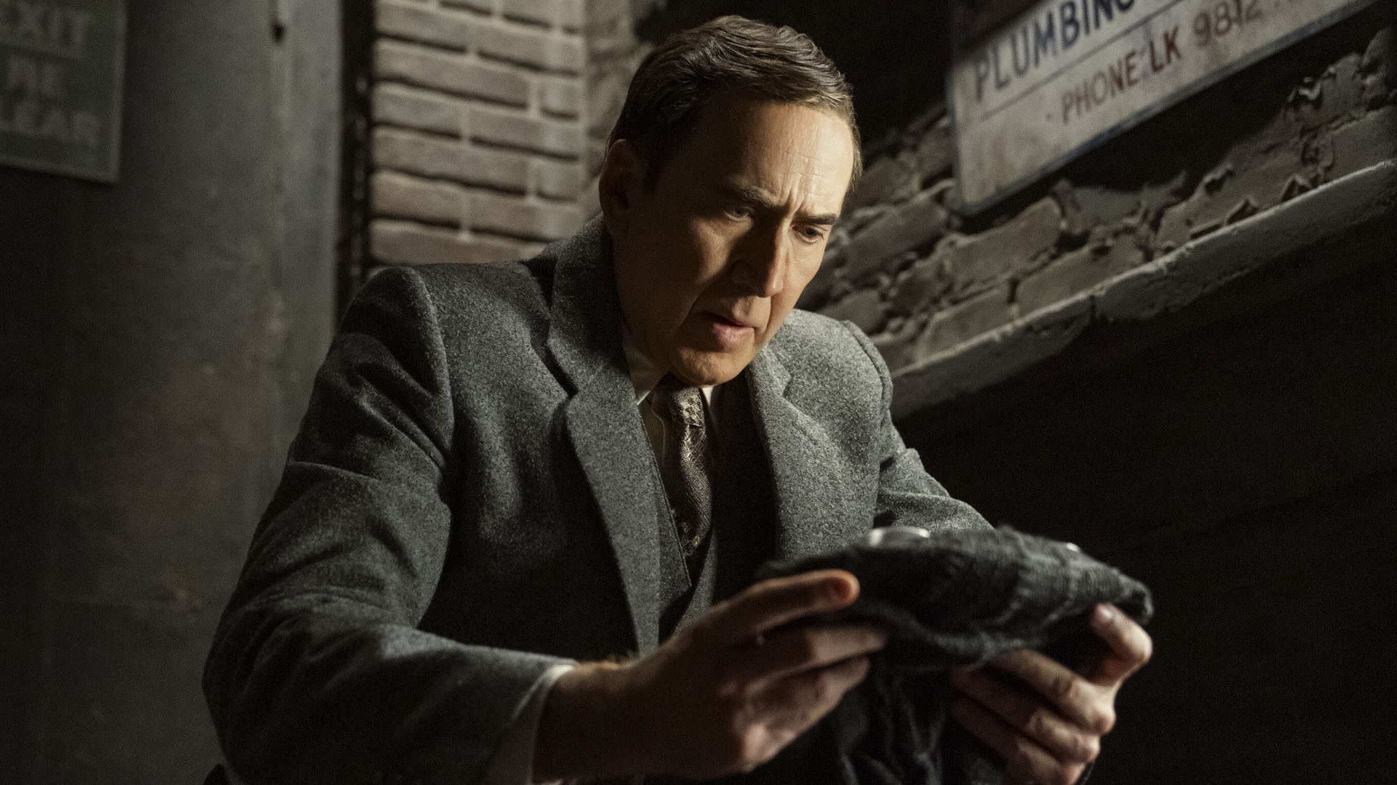 Ben Reilley (Nicolas Cage) looks at his mask on Spider-Noir.
